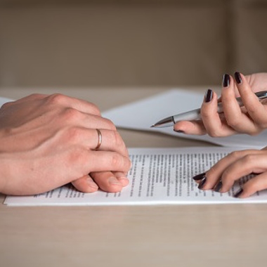 Divorced couple with divorce documents, one spouse refusing to sign
