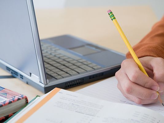 Person studying with laptop next to them