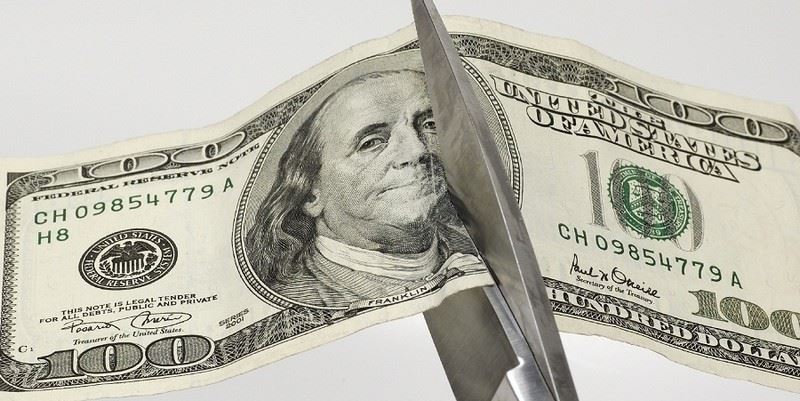 Scissors ripping a $100 bill